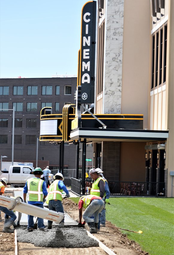 Crews pour the concrete for the sidewalk June 25 that will connect the Alamo Drafthouse Cinema to its parking lot when it opens this month.